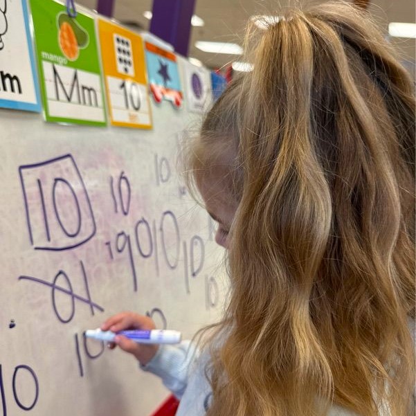 Preschool girl at The Club House childcare center writing on a whiteboard. Preschool girl at The Club House childcare center writing on a whiteboard.